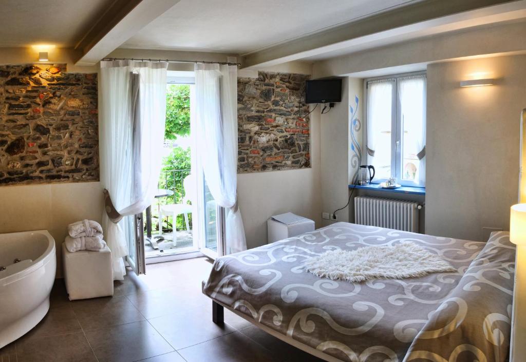 a bedroom with a bed and a tub and a window at Locanda di Orta in Orta San Giulio