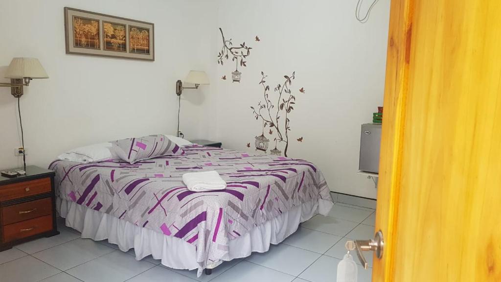 a bedroom with a bed with a purple and white blanket at Hotel Las Palmas in Esmeraldas