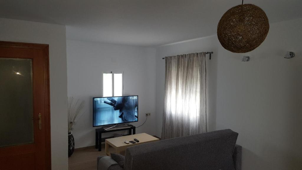 a living room with a couch and a flat screen tv at Apartamento Dúplex El Monumento in San Juan de Aznalfarache