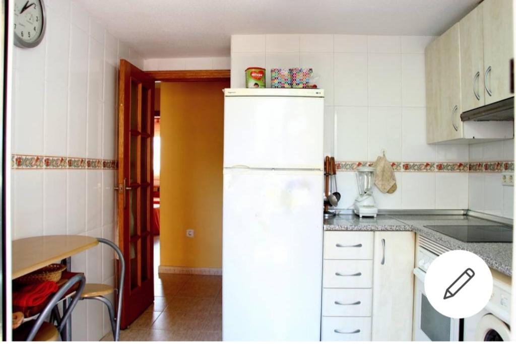 Una cocina con un refrigerador blanco y una mesa. en Precioso apartamento en la Manga, en La Manga del Mar Menor