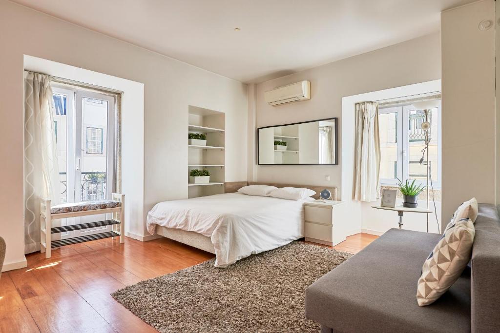 um quarto branco com uma cama e 2 janelas em Salgadeiras Suites - Bairro Alto em Lisboa