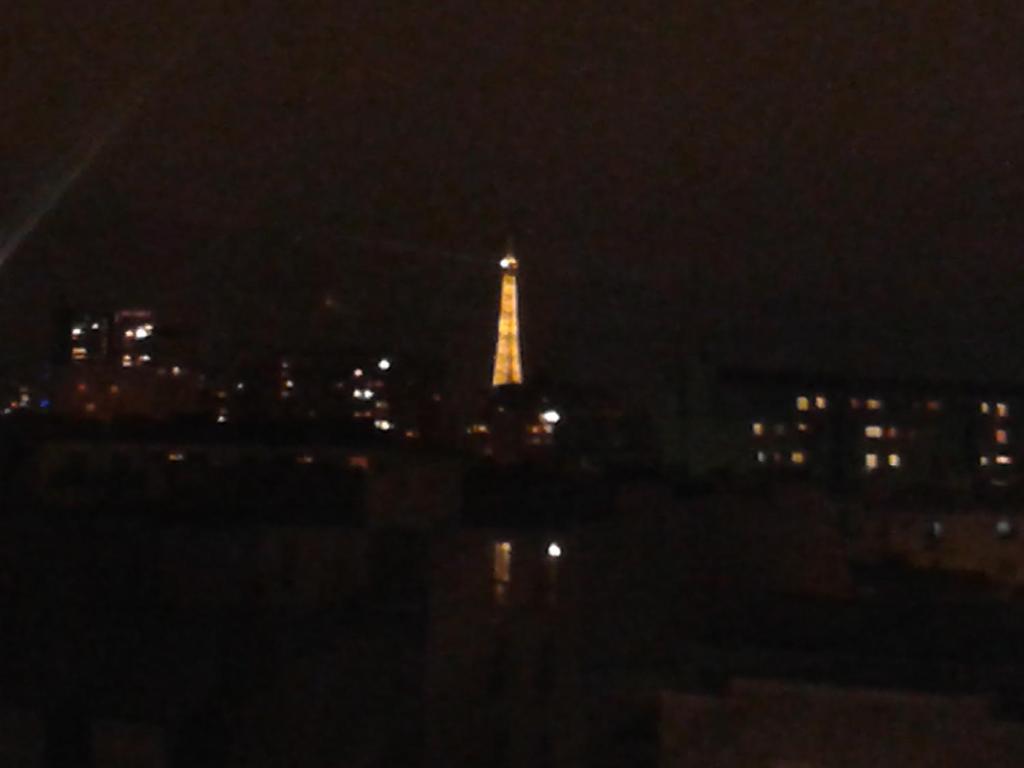 uma vista para a torre Eiffel à noite em Emmanuel & Béatrice em Paris