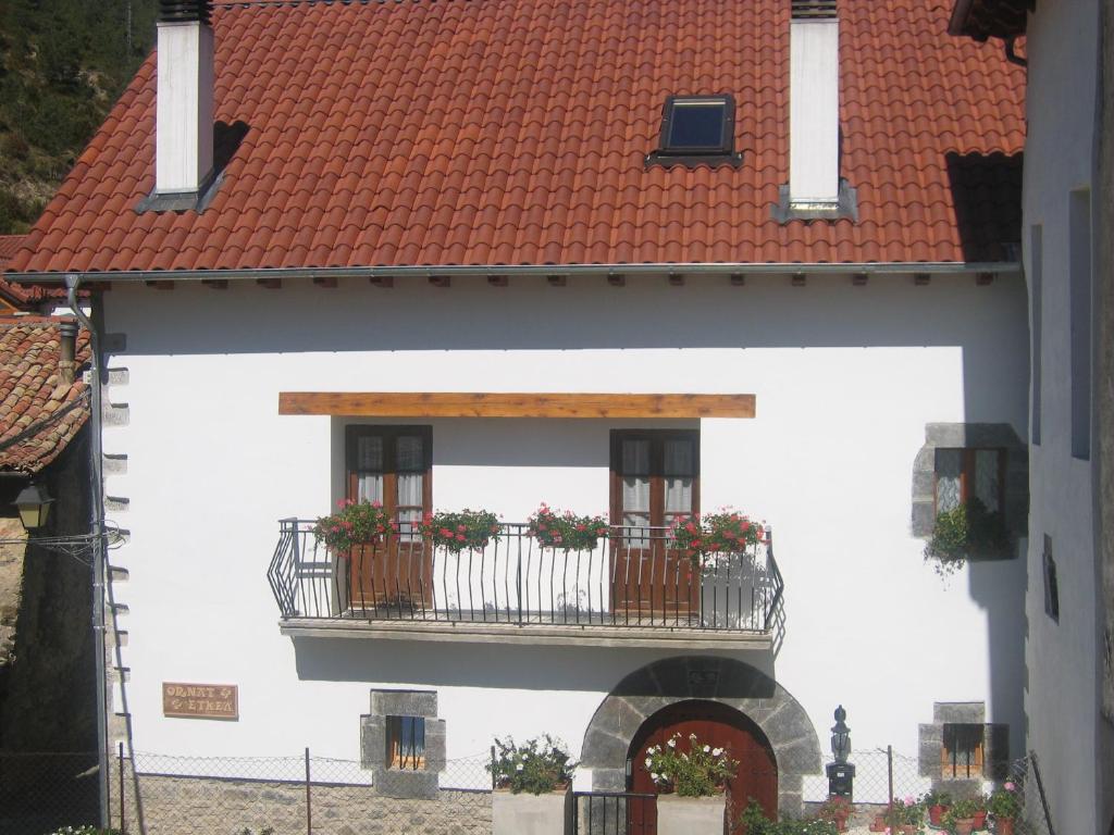 un edificio blanco con balcón y techo rojo en Casa rural Ornat Etxea en Vidángoz