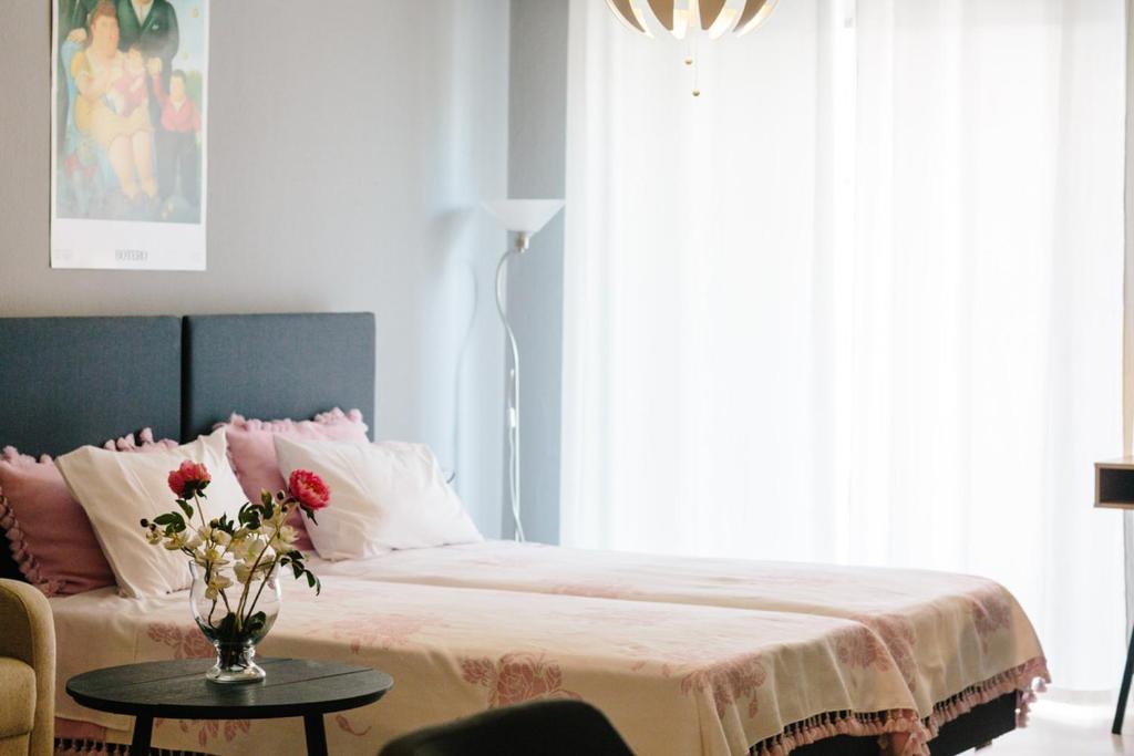 a bedroom with a bed with a vase of flowers on a table at Cosy Downtown Studio - Suite in Komotini
