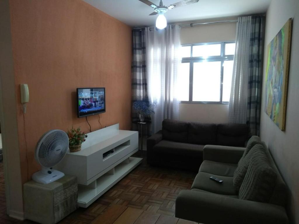 een woonkamer met een bank en een tv bij Apartamento Canto do Forte 200m da Praia in Praia Grande