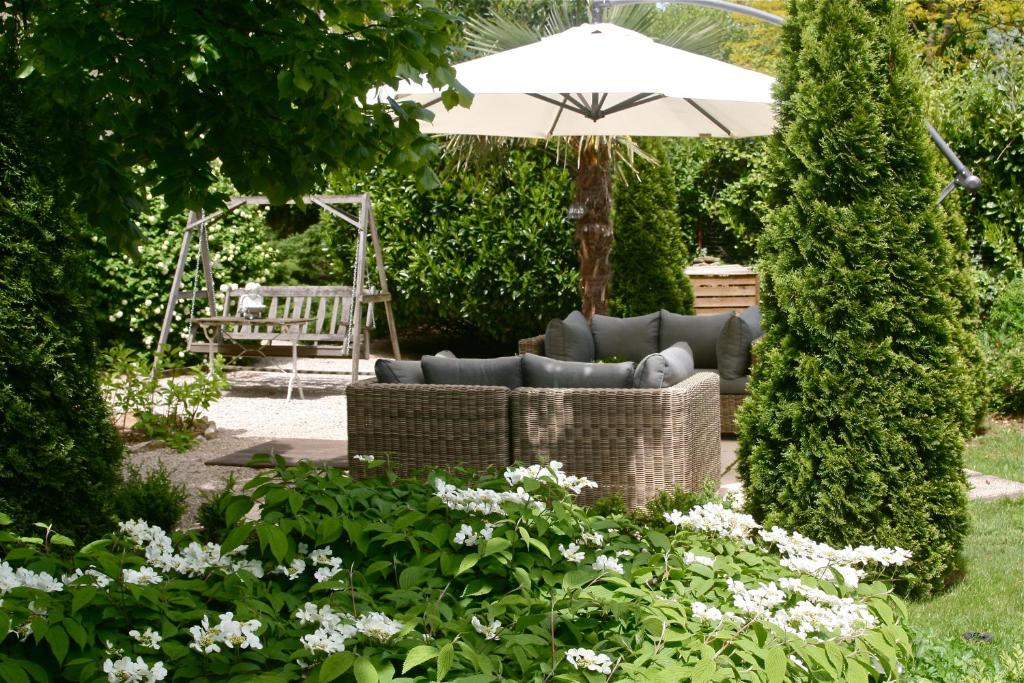 ブザンソンにあるChambre d'Hôtes La Villa Molinaのソファと傘付きの庭園