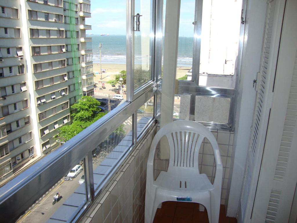 a white chair in a balcony with a view of the beach at Recanto Santista in Santos