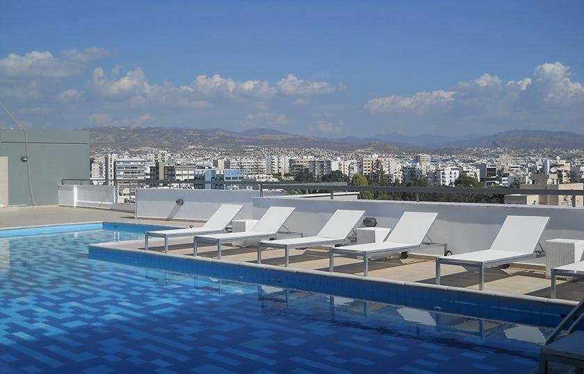 - un groupe de chaises longues blanches à côté de la piscine dans l'établissement Eden beach apartment 111, à Limassol
