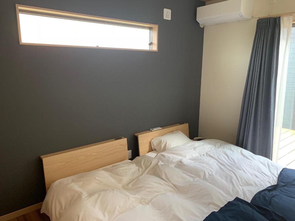 ein Bett in einem Schlafzimmer mit einem Fenster und einem Bett sidx sidx sidx in der Unterkunft KAI Ichinomiya in Ichinomiya