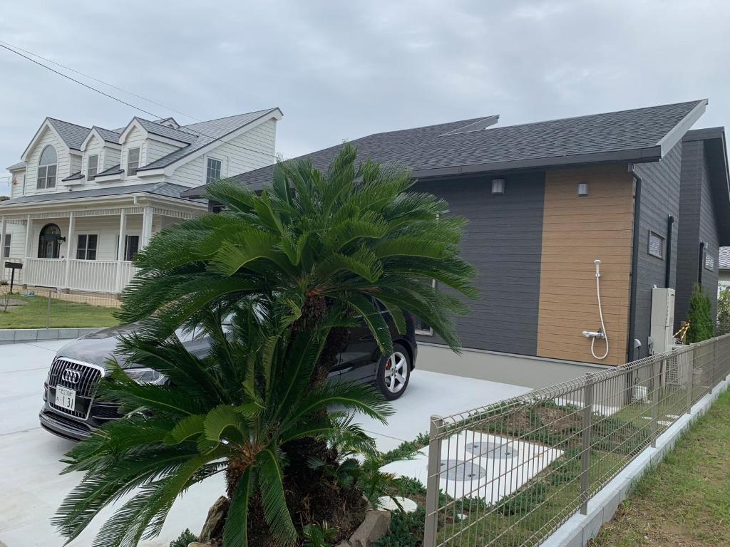 a car parked in front of a house with a palm tree at KAI Ichinomiya in Ichinomiya