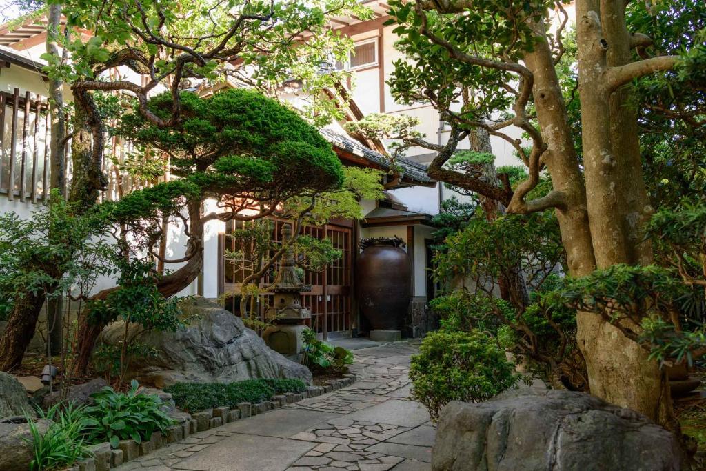einen Garten vor einem Haus mit Bäumen in der Unterkunft Atami Onsen Sakuraya Ryokan in Atami