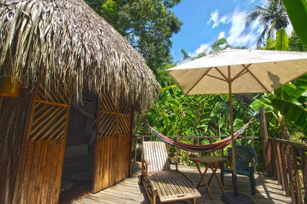 a hut with a chair and an umbrella at Tayrona Paradise in El Zaino