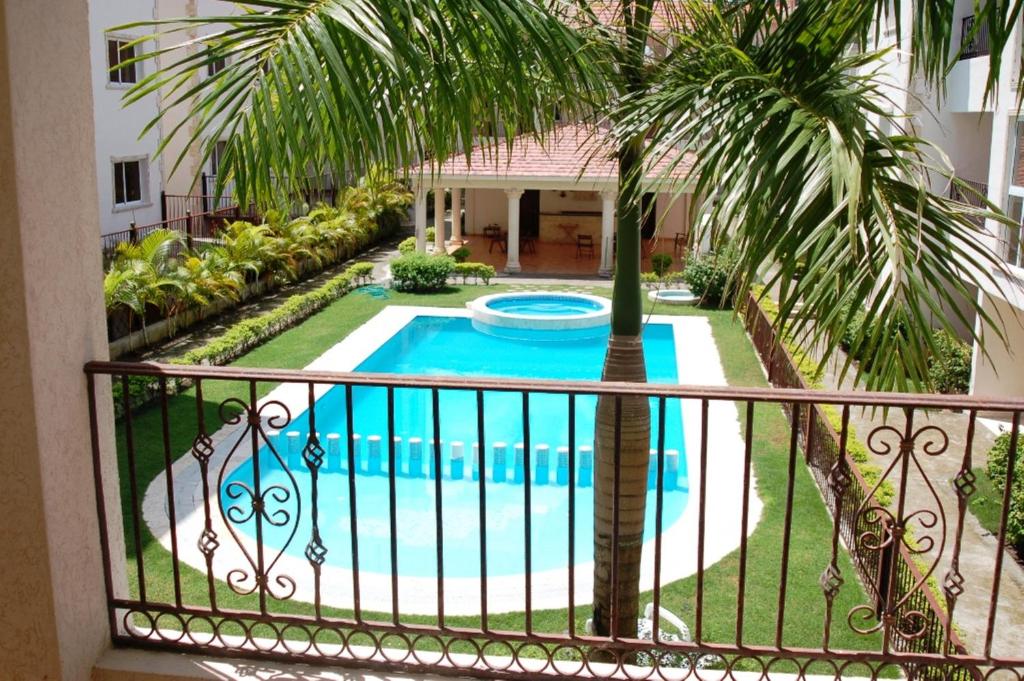 a balcony with a pool and a palm tree at Bavaro Green in Punta Cana