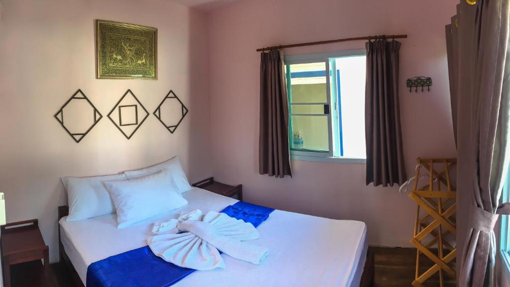 a bedroom with a bed with blue sheets and a window at Sangchan hostel in Ko Lipe