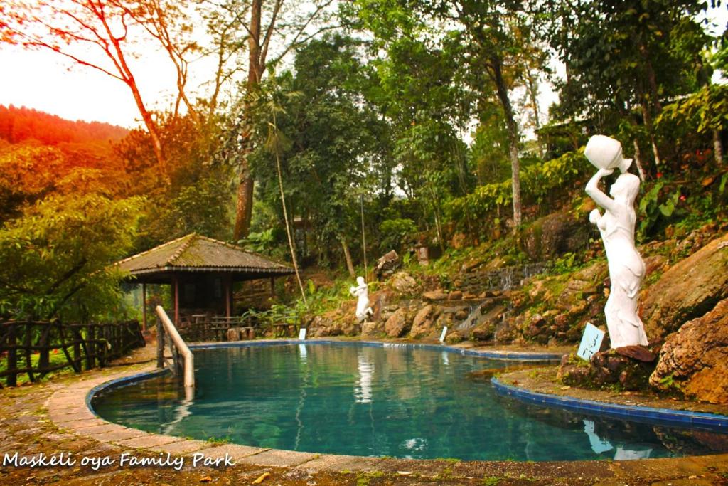 a pool of water with two white statues in it at Maskeli Oya Family Park in Norton Bridge