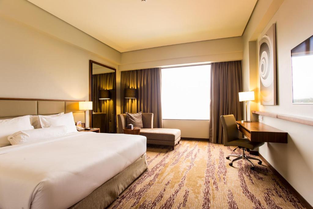 una habitación de hotel con una cama grande y una silla en I Hotel Baloi Batam en Nagoya
