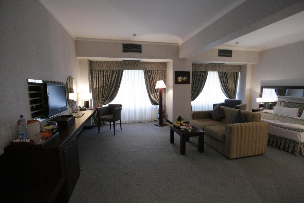 a living room with a couch and a tv in a room at Le Grande Plaza Hotel in Tashkent