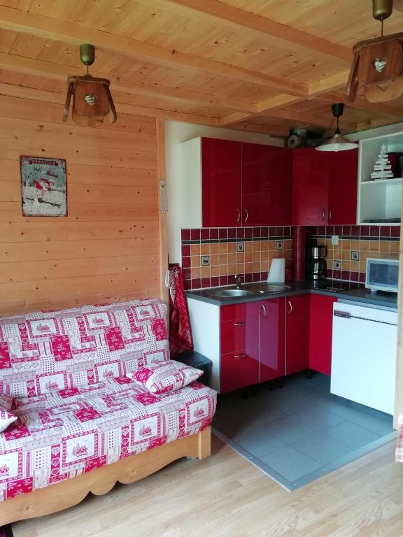 - une cuisine avec des placards rouges et un lit dans une chambre dans l'établissement MONT BLANC SOLEIL E-2, à Manigod