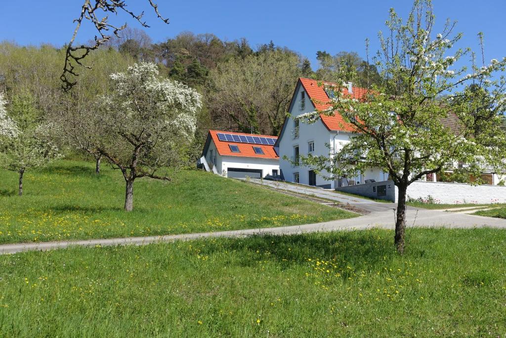 une maison blanche avec un toit orange dans un champ verdoyant dans l'établissement Ferienwohnung Süßenmühle, à Sipplingen