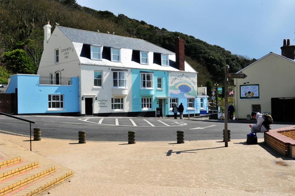 a large white and blue building on a street at Lulworth Cove Inn in Lulworth Cove