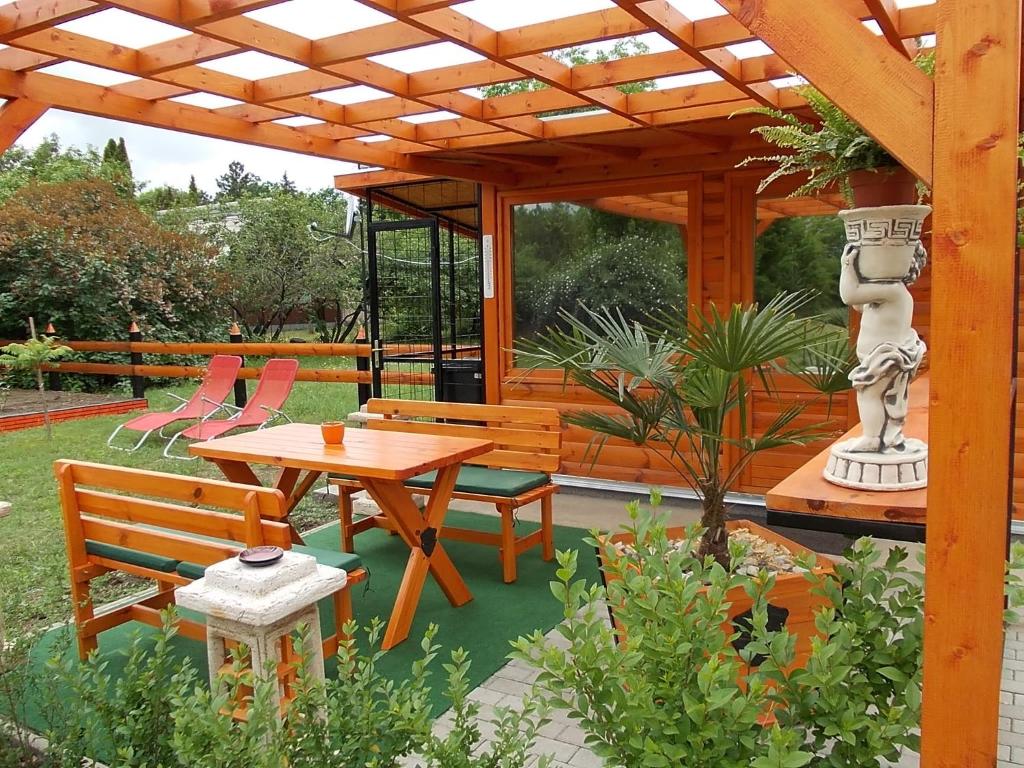 une terrasse avec une pergola en bois, une table et des chaises dans l'établissement Minilux Studio, à Berekfürdő