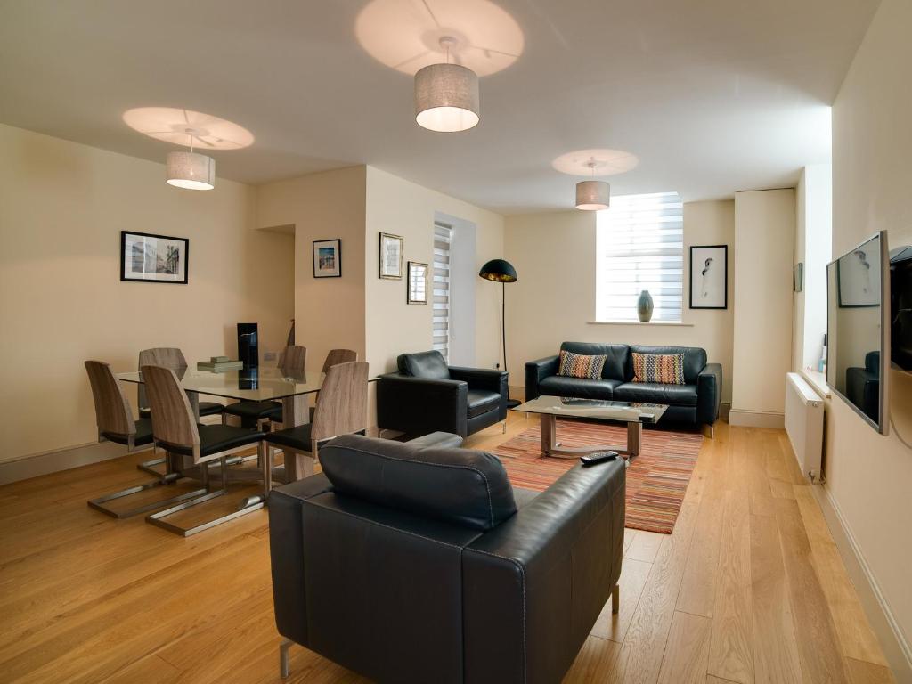 a living room with a black leather couch and a table at CS Serviced Apartments in Ulverston