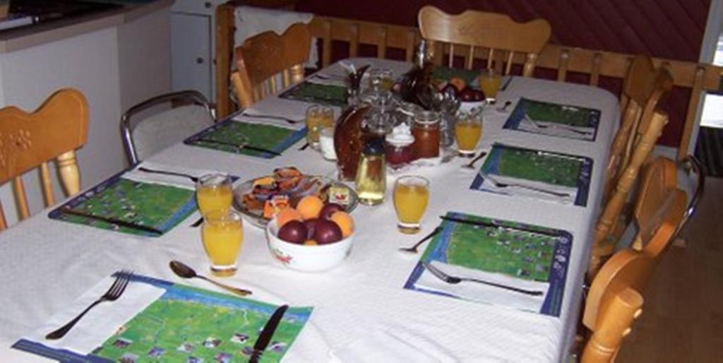 a long table with a white table cloth and a table with food and drinks at Gite La Ptite Falaise hébergement touristique in Sainte-Anne-des-Monts
