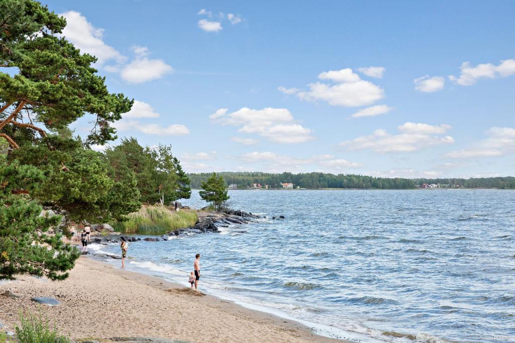 um grupo de pessoas em pé em uma praia perto da água em First Camp Skutberget-Karlstad em Karlstad