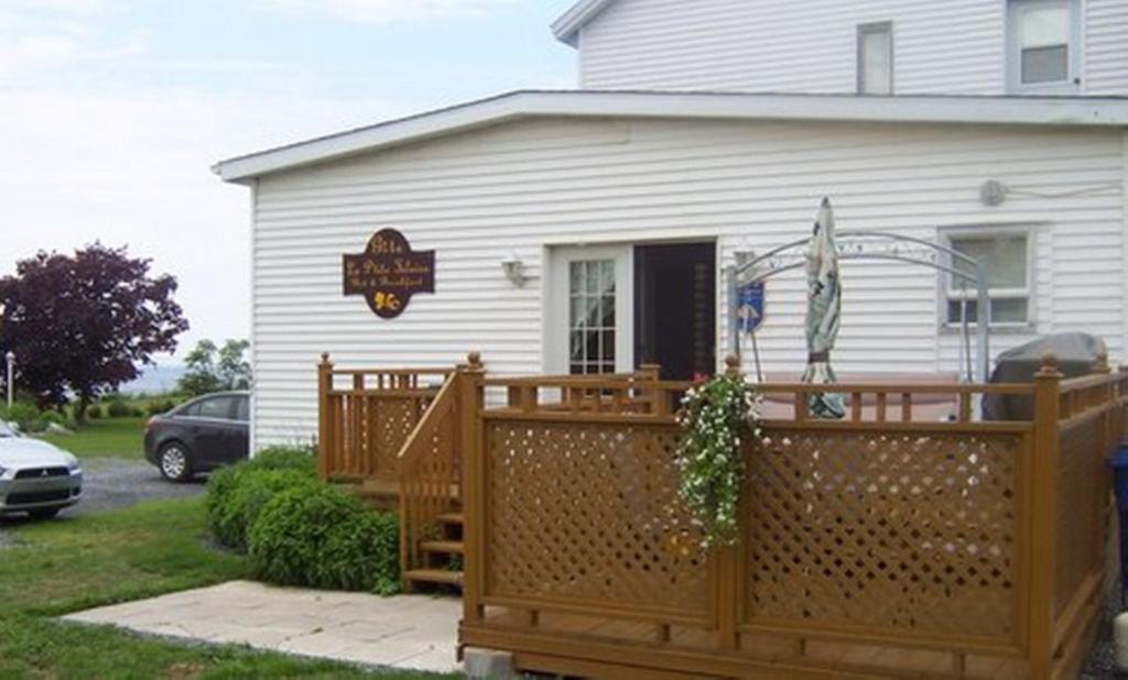 a house with a wooden fence in front of it at Gite La Ptite Falaise hébergement touristique in Sainte-Anne-des-Monts