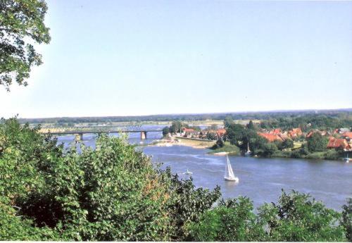 ein Segelboot auf einem Fluss mit einer Brücke im Hintergrund in der Unterkunft Hotel Bellevue in Lauenburg
