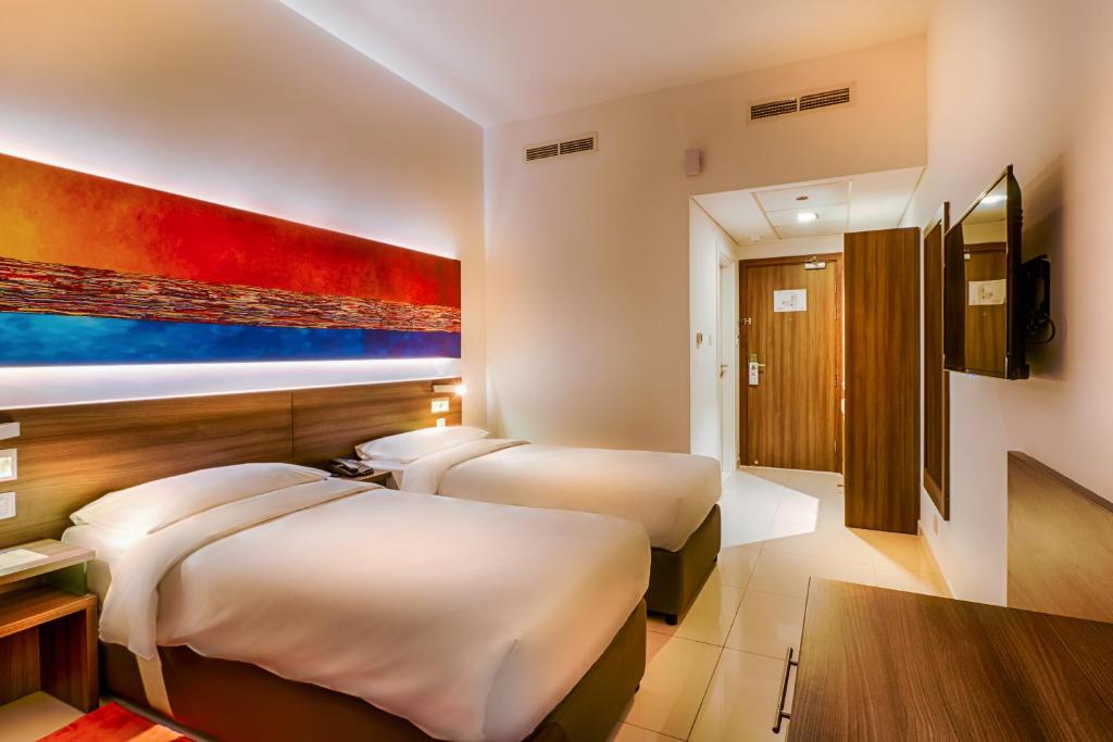 a hotel room with two beds and a painting on the wall at Citymax Hotel Bur Dubai in Dubai