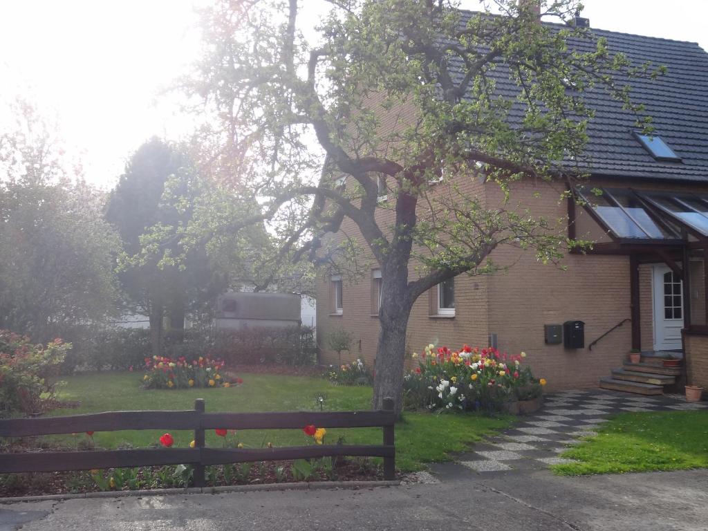 ein Haus mit einem Baum und einem Garten mit Blumen in der Unterkunft Ferienwohnung Grünewaldstraße 22 in Bünde