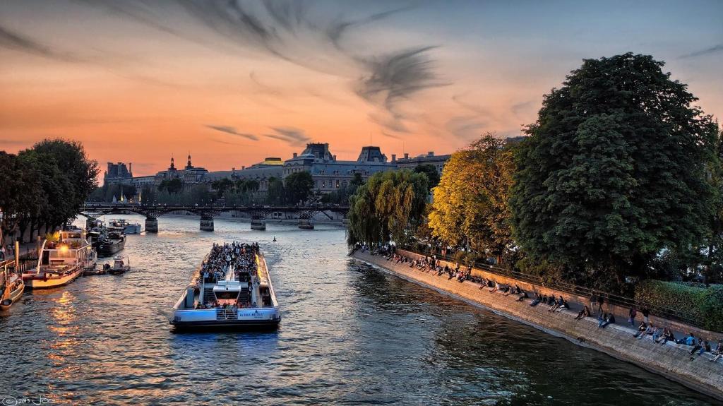 um grupo de barcos em um rio ao pôr do sol em 67 - Amazing Parisian Flat em Paris