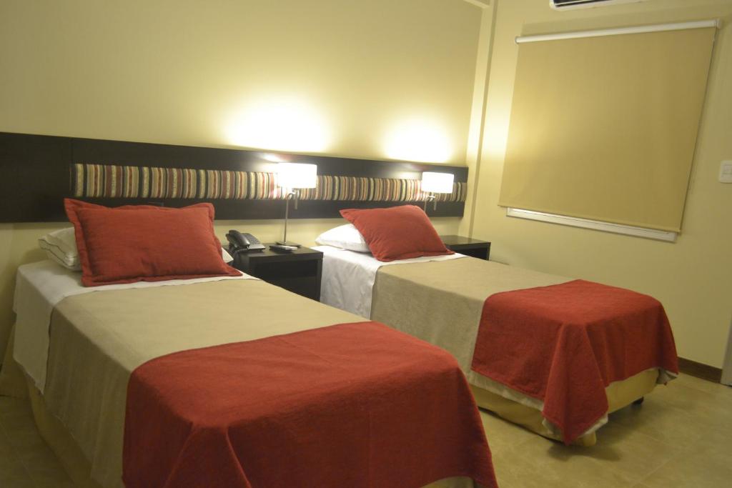 duas camas num quarto de hotel com lençóis vermelhos e brancos em Almuñecar Hotel em Tartagal