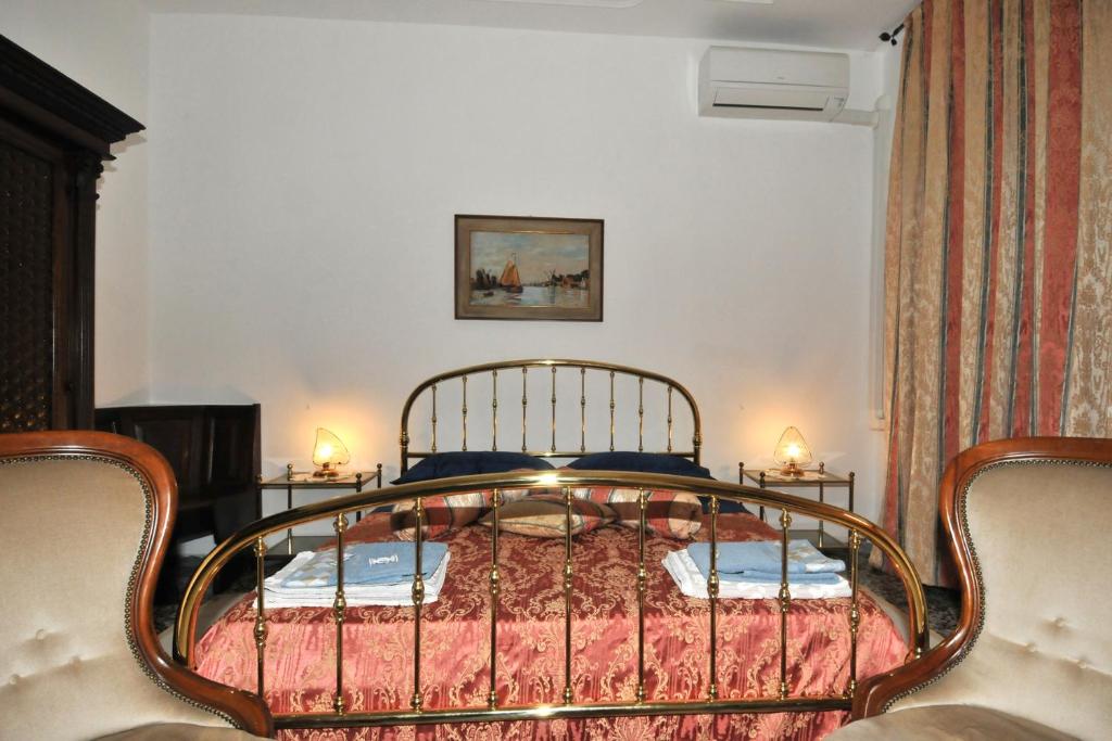 a bedroom with a bed with a metal frame and two chairs at Locazione Turistica Poker d'assi in Verona
