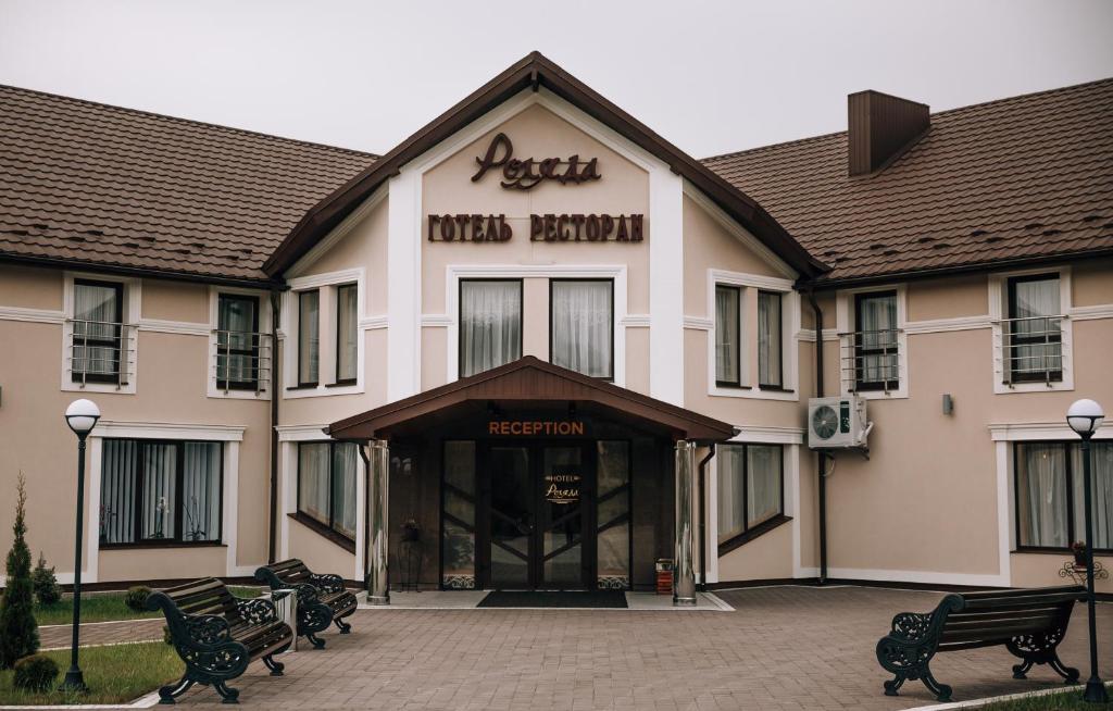 a hotel with benches in front of a building at Роляда in Tysmenytsya
