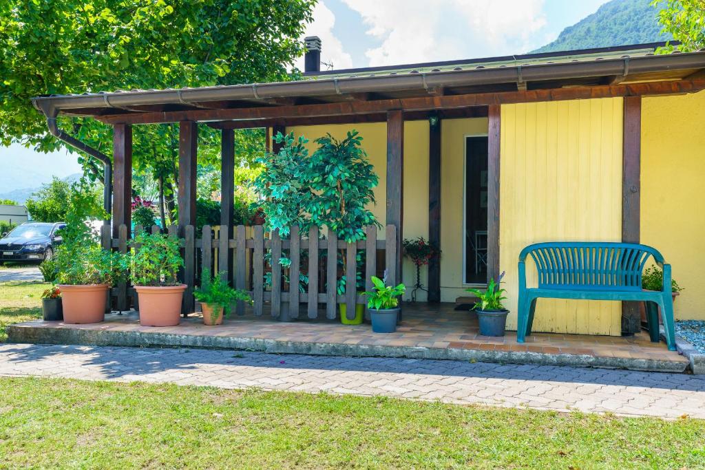 a blue bench sitting on a porch with potted plants at bungalow campeggio madonnina in Domaso