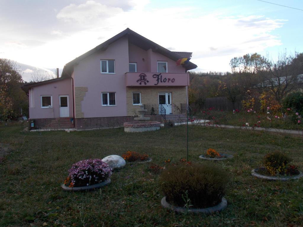ein Haus in einem Hof mit Blumen und Pflanzen in der Unterkunft Casa Floro in Comăneşti