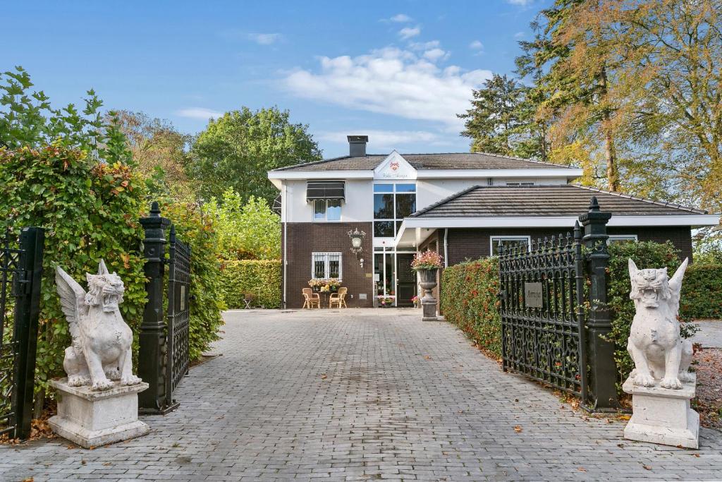 een oprit naar een huis met een poort met beelden bij Hotel Garni Villa Arrisja in Eefde