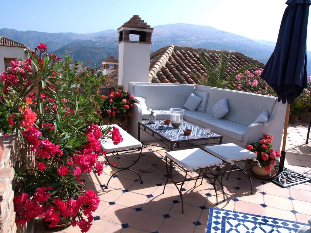 a patio with a couch and tables and flowers at Casa Aire de Lecrin in Pinos del Valle