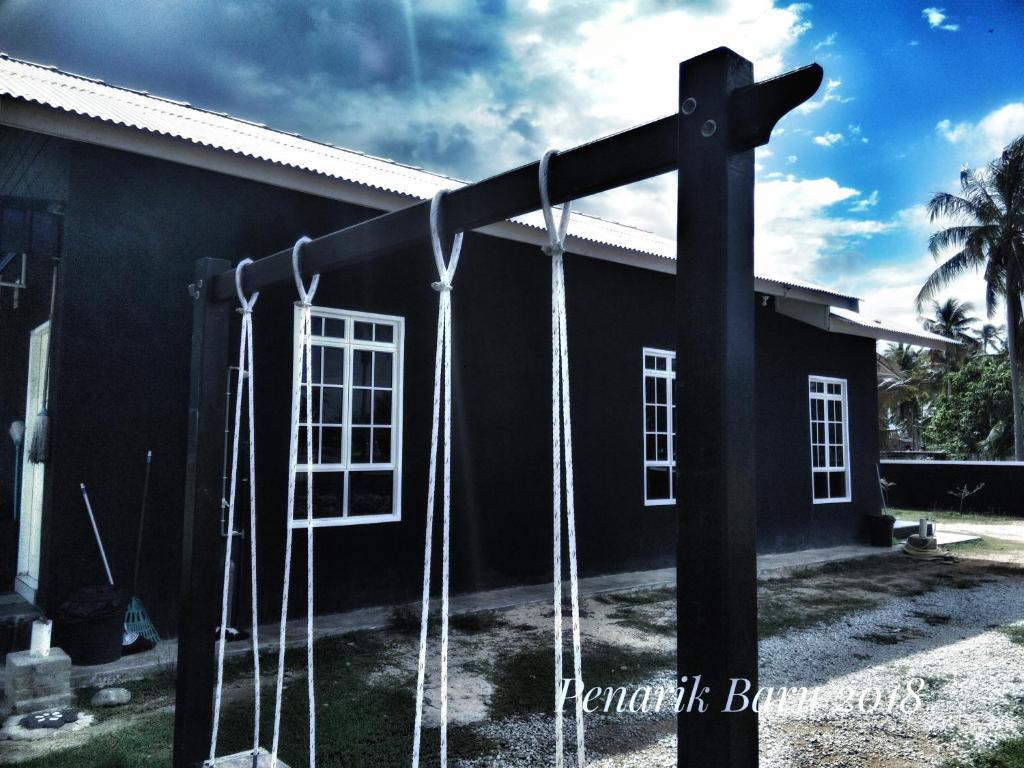 uma casa preta com um grande poste com baloiços em Penarik baru homestay em Kampung Penarik