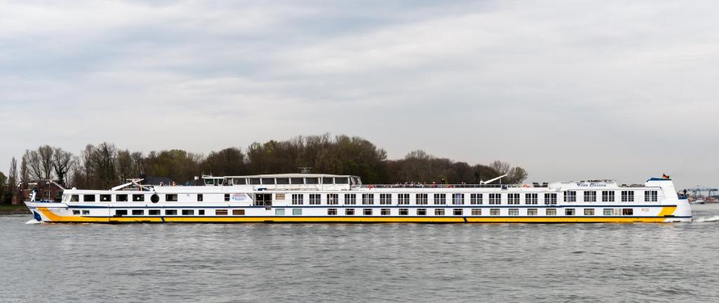 ein großes gelbes und weißes Boot auf dem Wasser in der Unterkunft Fairtours Hotelschiff Vista Classica **** in Düsseldorf