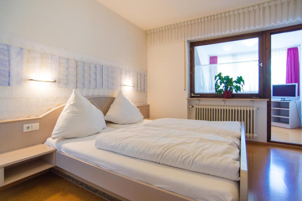 a bedroom with a large white bed with a window at Gasthaus Pension Löwen in Freiburg im Breisgau