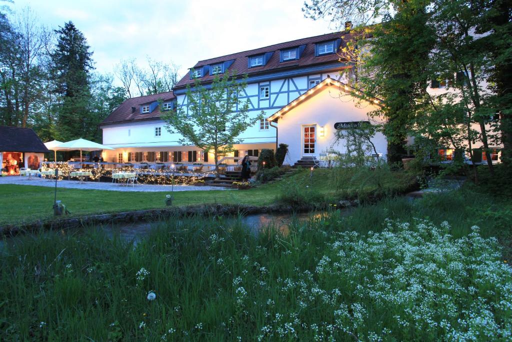une grande maison avec un étang en face de celle-ci dans l'établissement Naturglück Inselmühle, à Munich