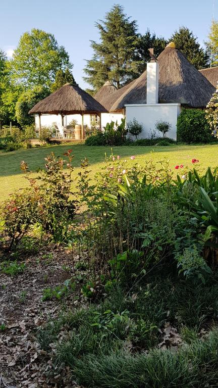 a house with a grass roof and a yard with flowers at Piccadilly Farm Cottages in Lions River