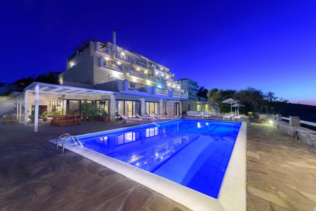 a large blue and white building with a pool at Cavos Bay Hotel & Studios in Armenistis