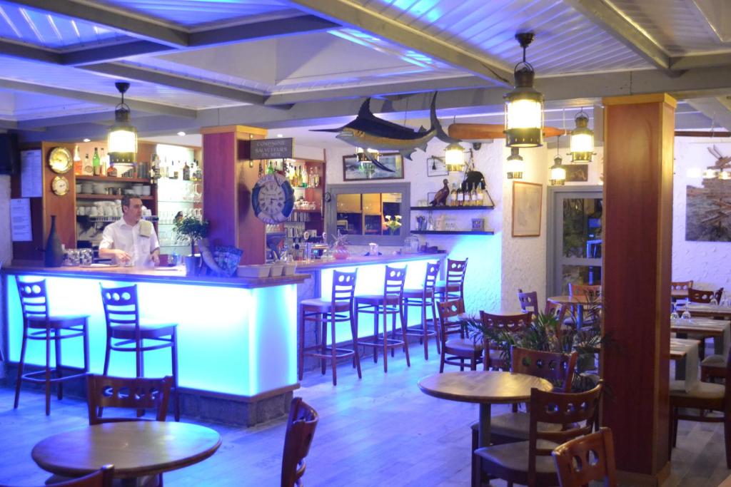 a bar in a restaurant with tables and chairs at Hotel De Bretagne in Saint-Pierre-Quiberon