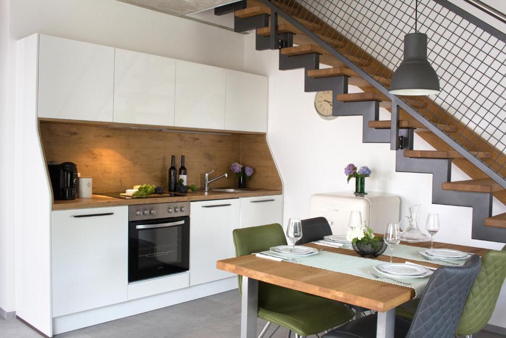 a kitchen with white cabinets and a table with green chairs at Zur alten Rebe Ferienhaus und Weingut in Konz