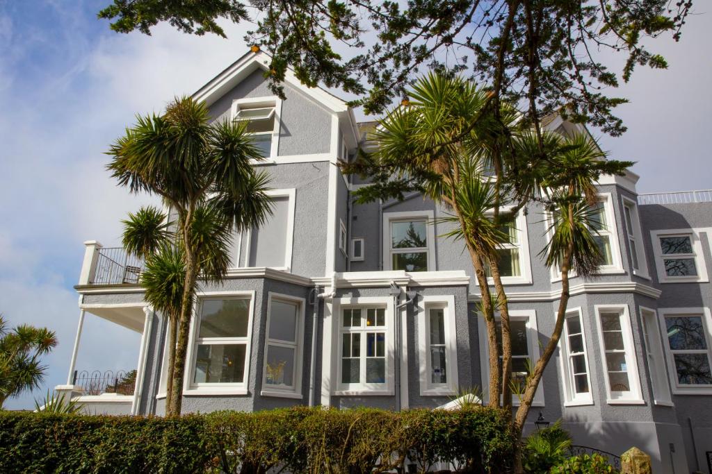 een wit huis met palmbomen ervoor bij The Lerryn in Falmouth