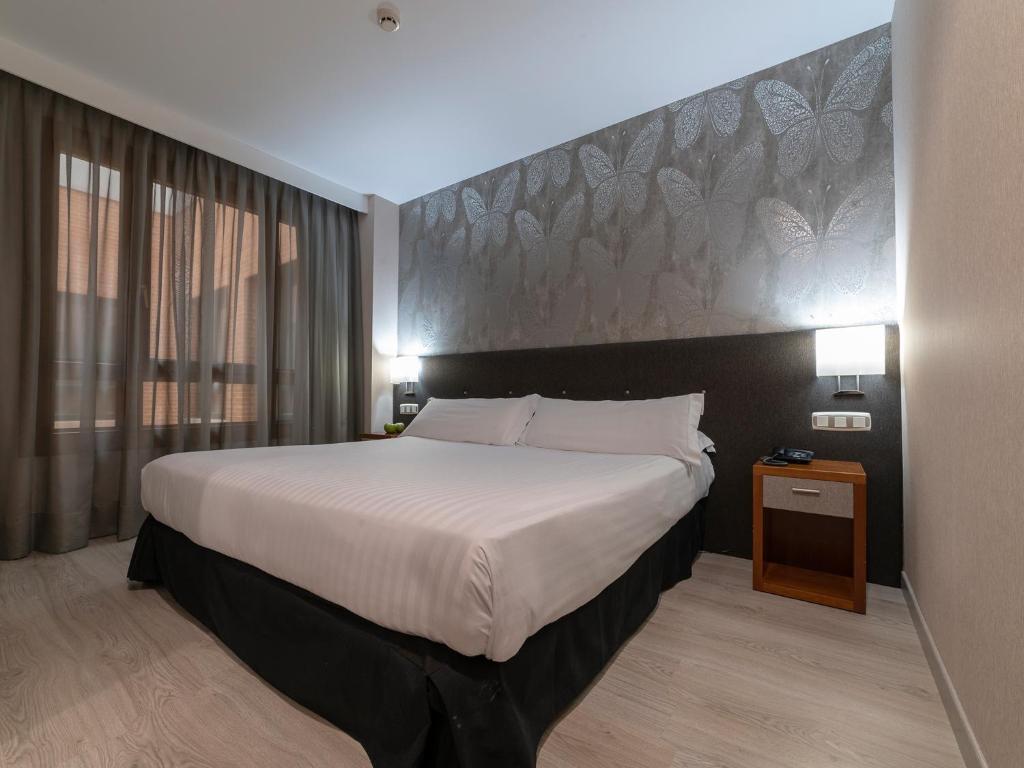 a hotel room with a large bed with a large headboard at Hotel Plaza Las Matas in Las Rozas de Madrid